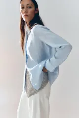 Camisa color coral confeccionada en lino 100%, de corte recto, con cuello solapa, manga larga con puños abotonados y cierre frontal con botones.