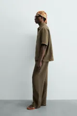 Camisa de corte relajado confeccionada en lino color verde militar, con cuello solapa, manga corta y cierre frontal de botones.