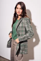 Blazer de corte recto con estampado de cuadros en tonos verdes y grises. Presenta solapas clásicas, cierre frontal y bolsillos laterales.