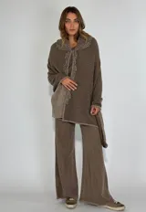 Ruana de lambswool color gris oscuro, con cuello alto y detalles bordados a mano en relieve en el cuello y a lo largo de la abertura frontal.