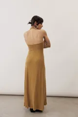 Vestido largo negro de corte al cuerpo con cuello halter y detalle de hebilla metálica dorada en el hombro con tira drapeada.