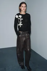 Chaqueta de punto negra con cuello redondo y manga larga. Presenta bordados florales en color blanco en la parte delantera y cierre frontal con botones.