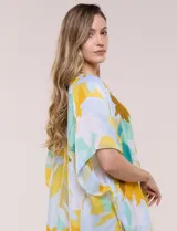 Kimono de gasa ligera con estampado floral en tonos amarillos, celestes, blancos y marrones, de manga corta amplia y diseño abierto con detalle de borlas en el ruedo asimétrico.