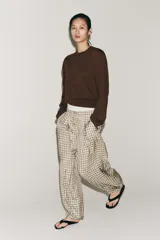 Pantalón de tiro medio con diseño de cuadros vichy en tonos neutros. Presenta pierna ancha, cintura elástica ajustable con cordones, bolsillos laterales y detalle de pinzas en el delantero.