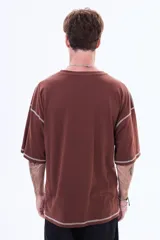 Remera negra de corte boxy con costuras a la vista en color blanco. Presenta un pequeño logo bordado en el centro del pecho y mangas cortas amplias.