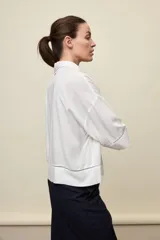Camisa de calce relajado color celeste, con mangas 3/4, cuello clásico y cierre frontal con botones. Presenta detalles calados en el frente y en las mangas que aportan un acabado delicado al diseño.