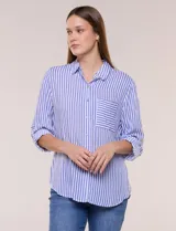 Camisa de corte clásico y silueta relajada con diseño de rayas verticales en blanco y negro. Presenta cuello camisero tradicional, cartera frontal con botones, un bolsillo aplicado en el pecho con rayas horizontales y mangas largas con sistema para arremangar.