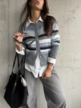 Saco tipo cardigan de punto con diseño de rayas horizontales en tonos gris, azul y blanco. Presenta cuello redondo, cierre frontal con botones y mangas largas.