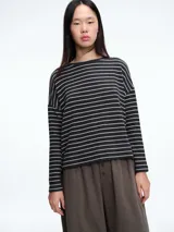 Buzo tejido de punto con diseño de rayas horizontales, cuello redondo y calce holgado con tajos laterales.