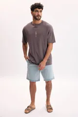 Bermuda de jean de color azul medio con lavado suave, corte holgado y largo por encima de la rodilla, con bolsillos clásicos.