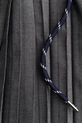 Pollera mini acampanada color gris oscuro, con tejido plisado, cintura elástica y cordón ajustable blanco y azul.