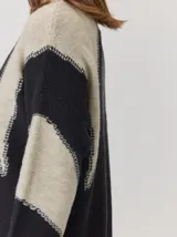 Buzo de tejido de punto con diseño de rayas verticales anchas en tonos beige y crema, cuello semipolera y manga larga.