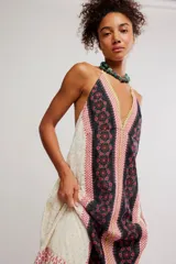 Vestido largo de tela liviana con estampado tipo patchwork de guardas florales en tonos negros, blancos y rosados, con escote en V profundo, tiras finas para anudar al cuello estilo halter y espalda descubierta.