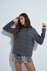 Sweater de punto gris con cuello a la base y diseño de trama geométrica en relieve. Presenta un calce relajado con mangas largas y puños tejidos.