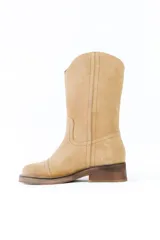 Bota de caña media confeccionada en cuero gamuzado color negro, con costuras a la vista en tono contrastante. Presenta un detalle de cadena metálica plateada con dijes colgantes en forma de llaves y candados alrededor del tobillo. Cuenta con un taco cuadrado de madera y suela de goma.