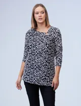 Blusa de tejido texturado con estampado de círculos blancos sobre fondo negro. Escote en V descentrado con aplique de aro metálico. Manga francesa y ruedo asimétrico.