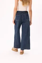 Jean de tiro alto con corte wide leg en lavado azul oscuro clásico. Presenta costuras a la vista y diseño de cinco bolsillos.