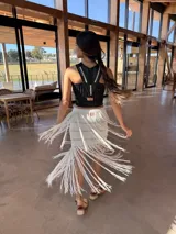 Falda midi tejida de algodón en color blanco, con diseño de punto acanalado y flecos largos en el ruedo que aportan movimiento.