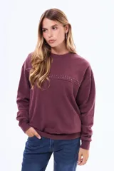 Buzo de cuello redondo en color bordó con efecto lavado, manga larga y detalle de tachas metálicas en la parte superior del pecho.