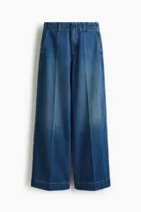 Pantalón de jean de tiro alto con corte wide leg y piernas amplias. Presenta diseño con raya frontal marcada, cierre con botón oculto, bolsillos laterales al bies y bolsillos traseros decorativos.