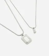 Kit de dos collares de cadena fina tipo serpiente en color plateado. Uno de los collares presenta un dije rectangular con borde grabado y el otro incluye un dije pequeño de forma orgánica.