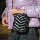 Bandolera negra de cuero sintético con diseño acolchado en forma de chevron. Tiene correa regulable con herrajes dorados, cierre superior y un bolsillo interno con cierre.