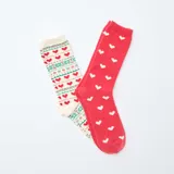 Pack de dos pares de medias de algodón, uno de color rojo con estampado de corazones blancos y otro de color crema con estampado navideño de corazones y motivos geométricos en verde y rojo.