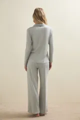 Conjunto de pijama compuesto por una camisa de manga larga con cuello solapa y cierre frontal de botones, y un pantalón de corte recto. Ambas prendas están confeccionadas en tejido de punto acanalado de color gris claro.