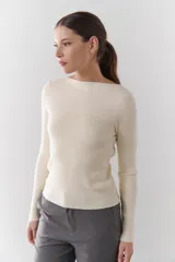 Buzo de morley color crema, con cuello bote y manga larga. Presenta un diseño de punto acanalado y un detalle de franja horizontal en el pecho.