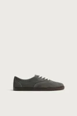 Zapatilla deportiva barefoot de hombre, confeccionada en piel con acabado serraje gris, con puntera ancha, cordones en contraste y suela fina de goma marrón.