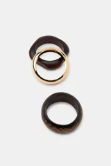 Pack de tres pulseras rígidas para mujer, compuesto por una pulsera metálica lisa dorada, una pulsera de madera lisa con diseño cuadrado y una pulsera de madera labrada con patrones geométricos en tono marrón oscuro.