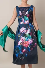 Vestido italiano azul con estampado floral en tonos rosa, blanco y verde. Presenta detalle de encaje en el escote, corte a la cintura y falda con tablas.