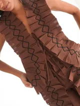 Top sin mangas color marrón, con escote en V profundo y solapas plisadas con bordado de hilo negro en patrón de rombos. Presenta un lazo de ajuste frontal.