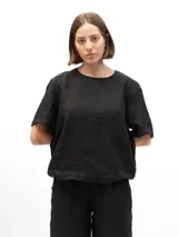 Remera de lino con cuello redondo, mangas cortas y calce relajado. Presenta un diseño minimalista con detalle de botones en la espalda.