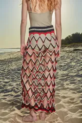 Falda larga tejida a crochet con diseño de red y patrón de rombos en colores negro, rojo y blanco. Presenta una cintura elástica tejida en color negro.