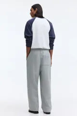 Pantalón jogger de punto de algodón gris melange, de corte relajado y perneras rectas con pliegue frontal cosido. Presenta cintura elástica con cordón ajustable, bolsillos laterales y falsas braguetas decorativas.