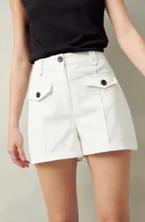 Short de algodón de tiro alto, color beige, con bolsillos delanteros tipo parche con solapa y botones a la vista.