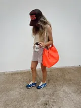 Bandolera grande de nylon reciclado color coral neón, con cierre de cordón ajustable y correa larga regulable.