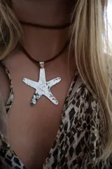 Collar de cordón marrón con dije colgante en forma de estrella de mar plateada con textura martillada.