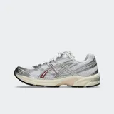Championes Asics modelo Gel 1130, color blanco con detalles plateados y verde oscuro. Diseño retro inspirando en el running con tecnología GEL en el talón.