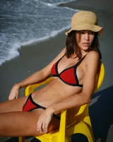 Conjunto de bikini rojo de lúrex con breteles y vivos negros. El corpiño es de triángulos fijos con breteles regulables y la bombacha es vedetina con breteles laterales regulables.