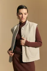 Chaleco de paño color marrón oscuro, de silueta recta y diseño minimalista. Presenta cuello a la base, cierre frontal con botones claros y bolsillos aplicados.