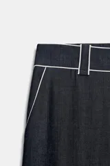Pantalón de tiro medio de pernera ancha, color azul marino, con bolsillos delanteros y detalle de vivos en contraste de color blanco. Cierre frontal con cremallera y botón.