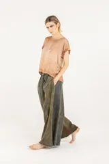Pantalón palazzo de denim con doble pinza, tiro alto y pierna extra ancha con ruedo deshilachado. Presenta un efecto de teñido degradé irregular en tonos verde militar y marrón, cierre con botón y bolsillos laterales.