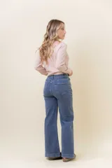 Pantalón de jean estilo wide leg, color celeste claro, con tiro medio, cinco bolsillos y cierre frontal con botón y cremallera.