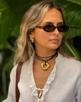 Collar con dije de forma irregular en tonos dorados y plateados, suspendido de un cordón doble de algodón negro.