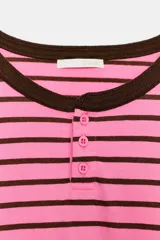 Camiseta estilo panadera de manga larga, con diseño a rayas horizontales en color rosado y marrón. Presenta cuello redondo con ribete marrón a contraste y cierre frontal parcial con tres botones pequeños.