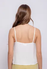 Top blanco de tirantes finos, escote en V con fruncido central ajustable mediante lazos.