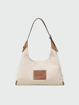 Cartera tipo hobo de Marc Jacobs, confeccionada en lona color beige con detalles en cuero negro. Presenta el logo estampado en el frente y una correa de hombro ajustable.