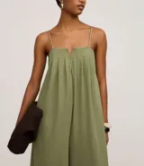 Mono de mujer color verde oliva, de pierna ancha y tiro alto, con escote recto y fruncidos en el busto. Los breteles son finos y trenzados en dos tonos.